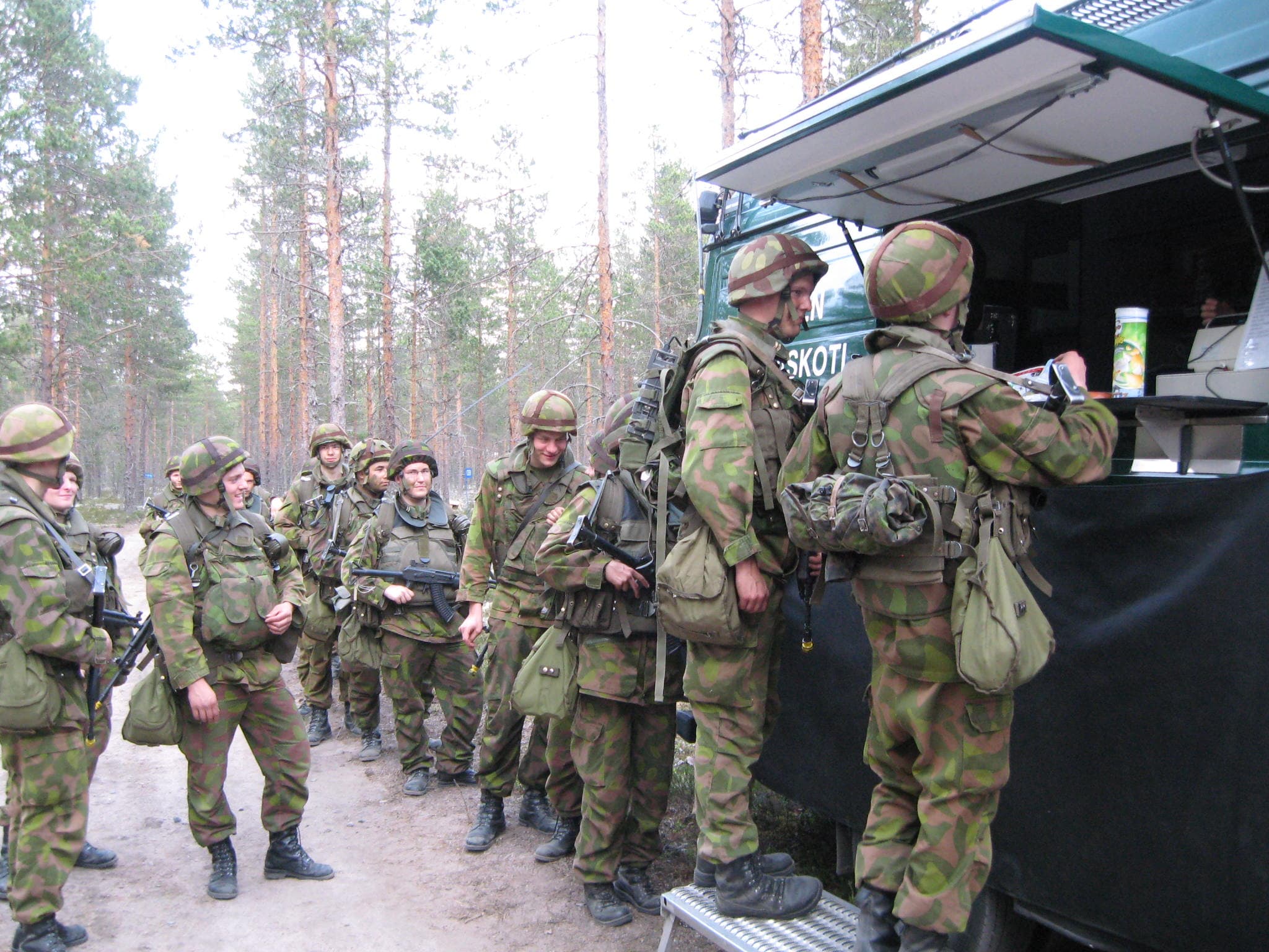 Varusmiehet jonottavat sotilaskotiautolla.