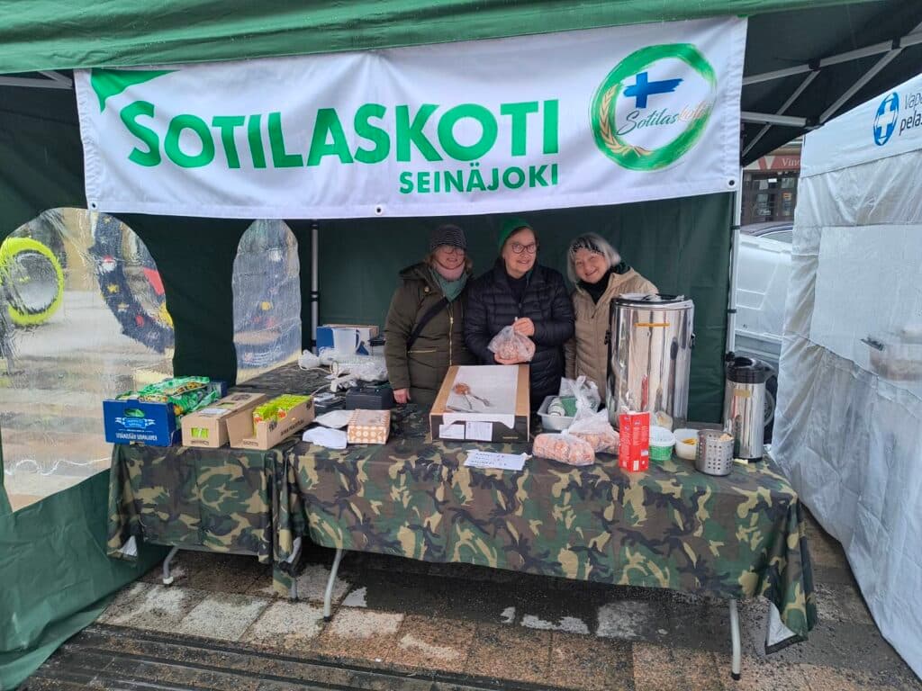 Hymyilevät sisaret sotilaskotikahviopöydän takana