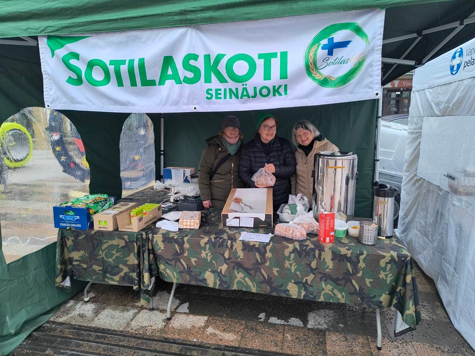 Hymyilevät sisaret sotilaskotikahviopöydän takana